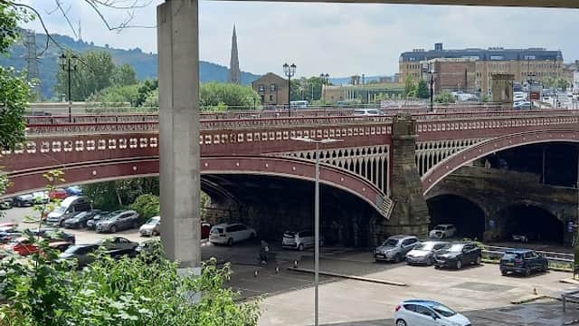 North Bridge Car Park in Halifax, featuring multiple levels, vehicles, and surrounding greenery under a cloudy sky.