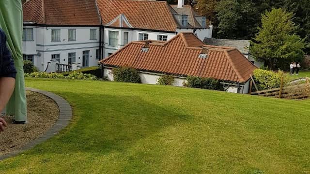 Welton Lodge features a charming hotel building with red-tiled roofs, surrounded by lush green lawns and trees.