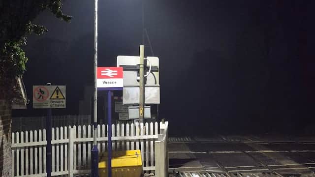 Wressle bus stop at night, featuring a lit platform, railway tracks, and surrounding dark, foggy atmosphere.