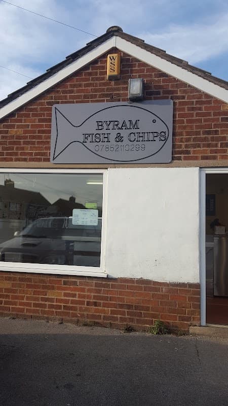 Sign for Byram Fish and Chips on a brick building, featuring a fish graphic and contact number.