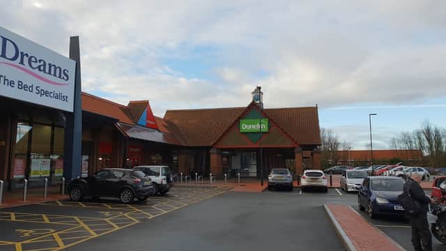 Dunelm store entrance with a red roof, surrounded by parked cars and a cloudy sky in Wortley, Yorkshire.