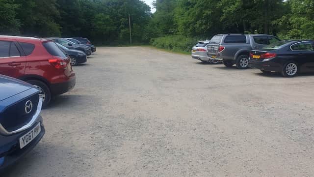 Gravel parking lot with several cars surrounded by trees at Fountains Abbey in Sawley, North Yorkshire.
