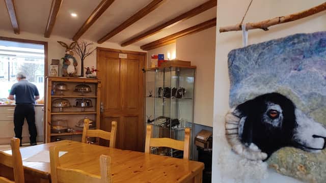 Cozy tea room interior with wooden beams, a dining table, and a decorative sheep portrait on the wall.