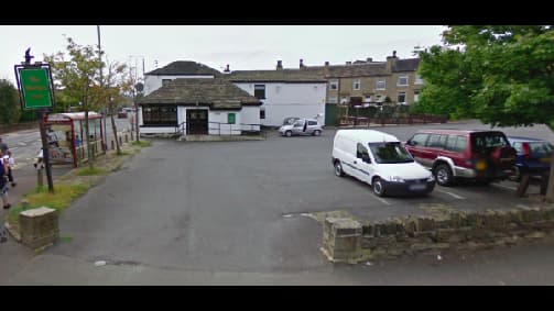 Pay & Display parking area in Brighouse, Yorkshire, with vehicles parked and a building in the background.