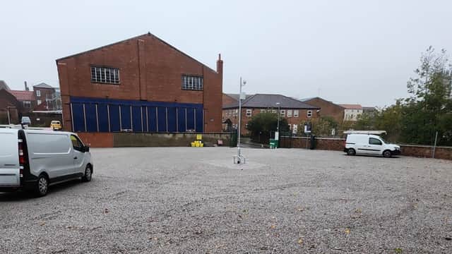 Gravel car park with two white vans, surrounded by brick buildings and a foggy sky in Driffield, Yorkshire.