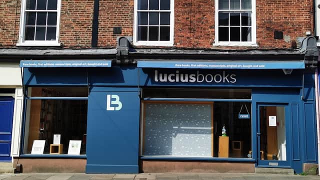 Charming bookshop exterior with large windows, blue signage, and a display of rare books in York, Yorkshire.