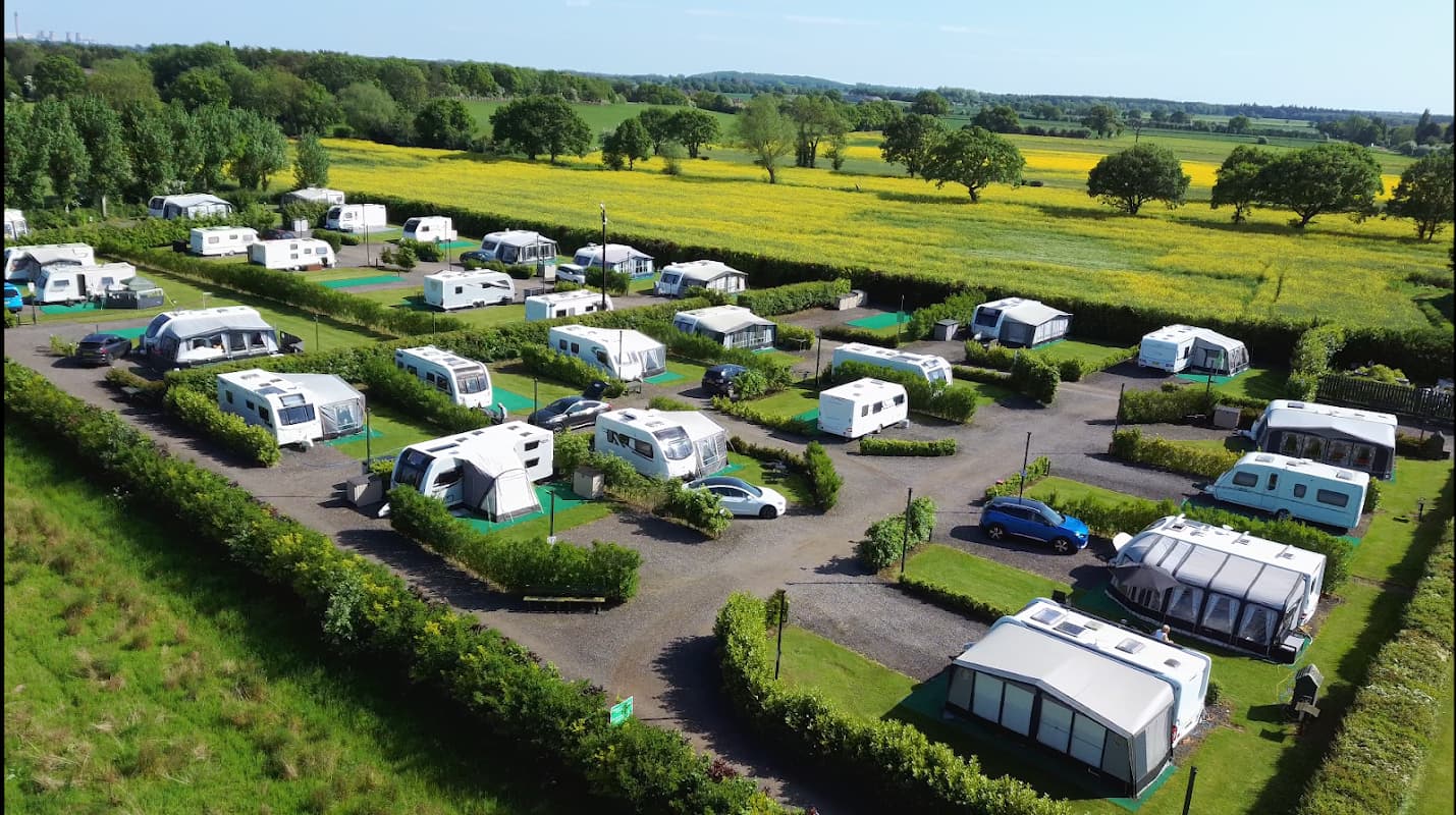 Holiday lodges and seasonal pitches in a lush green landscape, surrounded by fields and trees in Cawood, Yorkshire.