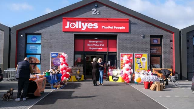 Exterior of Jollyes pet shop in Harrogate, featuring colorful banners, balloons, and pet supplies displayed outside.