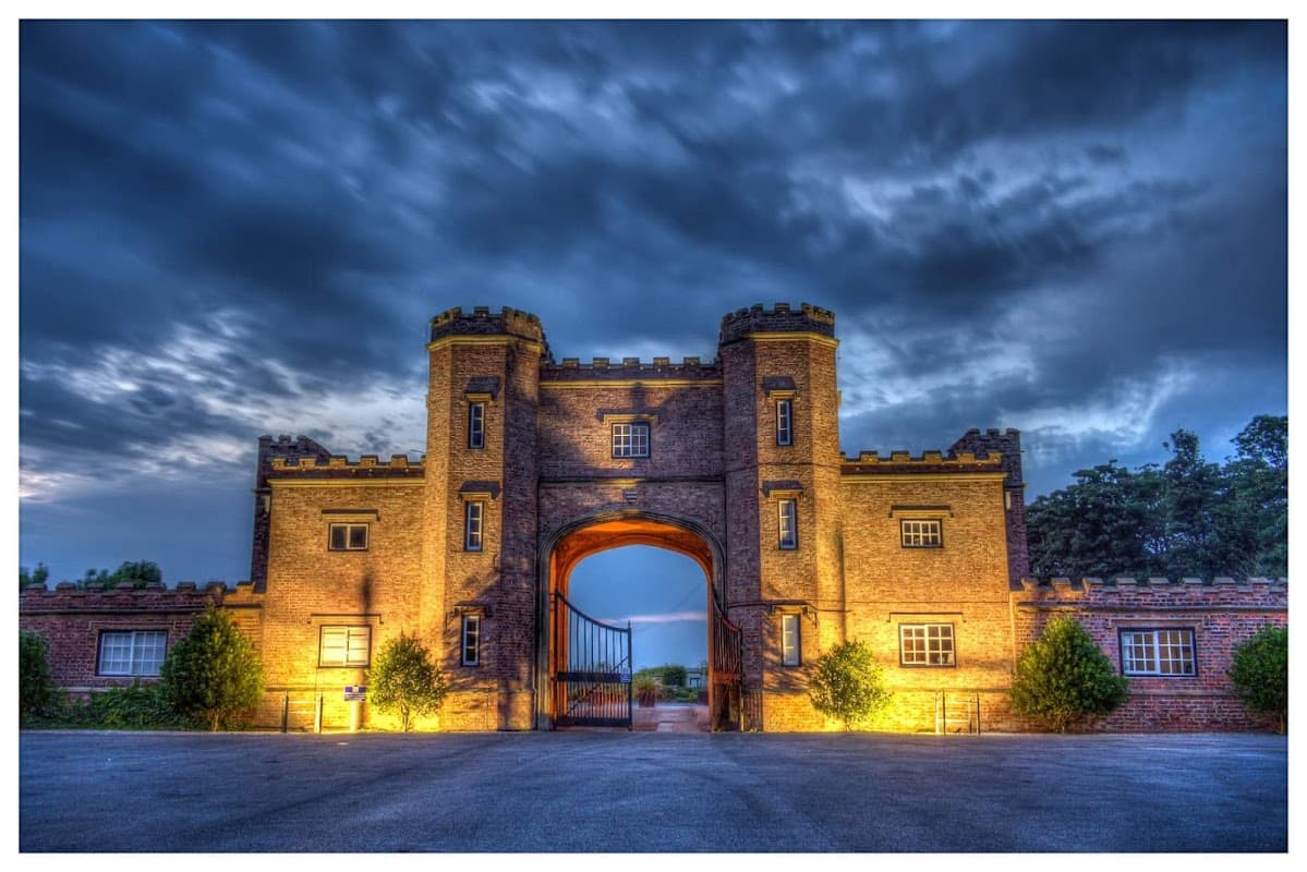 Historic castle-style entrance with towers, illuminated under a dramatic sky at Burton Constable Holiday Park.