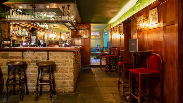Warm wooden interior with a bar, stools, and dim lighting, creating a cozy atmosphere in Craven Heifer, Stainforth.