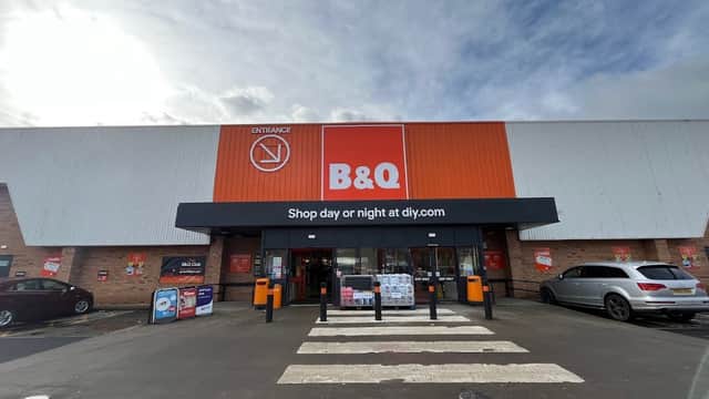 B&Q store entrance on Penistone Road, featuring a large orange and white sign, with parking and crosswalk in front.