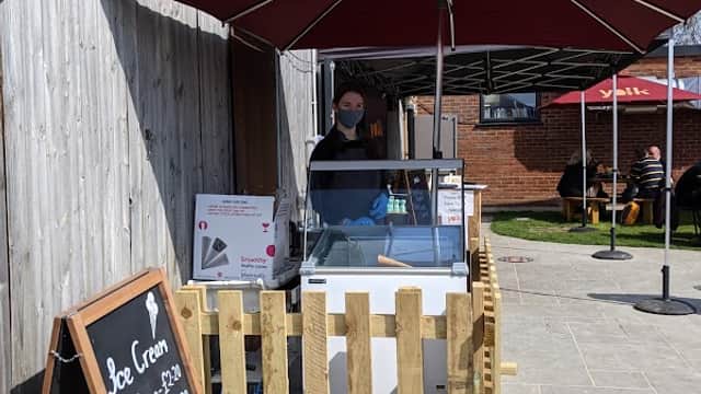 Yolk Farm café with an ice cream stand under an umbrella, wooden fence, and outdoor seating area.