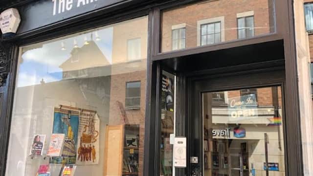 The Amnesty Bookshop features a black storefront with large windows displaying colorful books and a welcoming entrance.