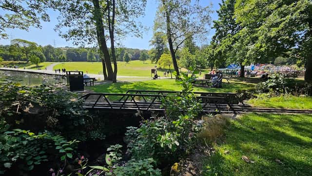 View of Mereside Car Park with greenery, trees, and people enjoying a sunny day in Halifax, Yorkshire.