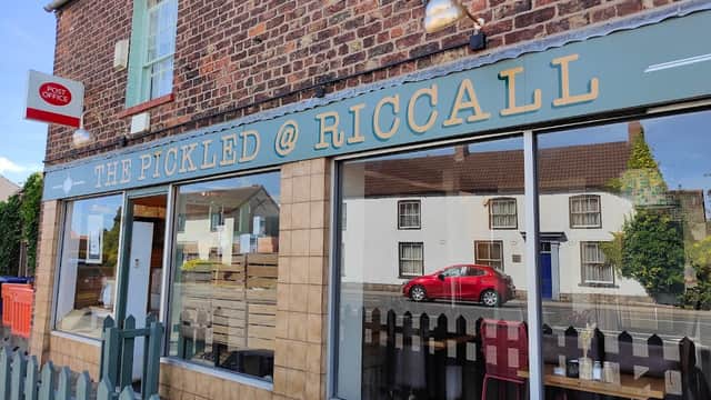 The Pickled @ Riccall sign on a brick building with a red car parked outside and a fence in front.