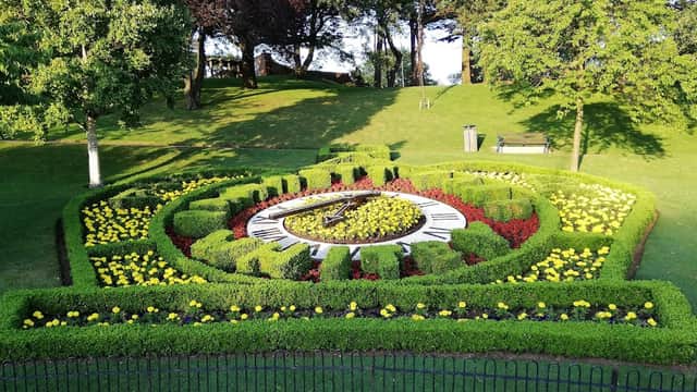 Colorful flower beds in a circular design, surrounded by lush green grass and trees in Pannett Park, Whitby.