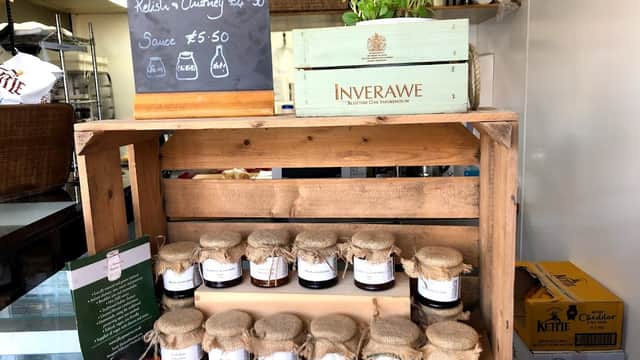 Wooden display with jars of jam and chutney, a potted herb, and a chalkboard menu at Pattacakes bakery.