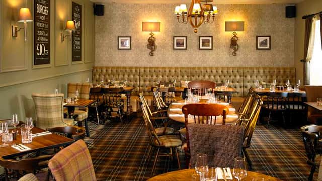 Elegant restaurant interior featuring wooden tables, upholstered seating, and decorative wall sconces in a cozy atmosphere.