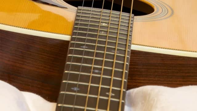 Close-up of an acoustic guitar's neck and body, showcasing its strings and sound hole.