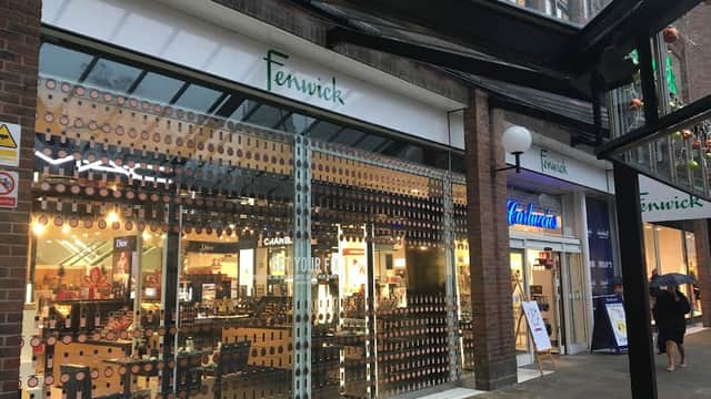 Fenwick store entrance with large glass windows, showcasing displays and signage, in a shopping area in York.