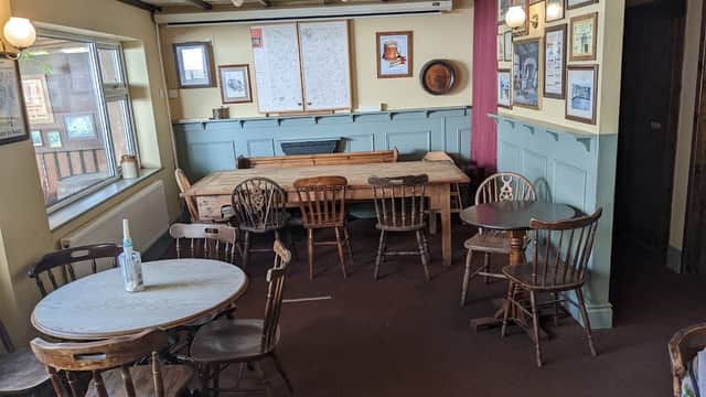 Cozy bar interior with wooden tables and chairs, framed pictures on the walls, and a large map on display.