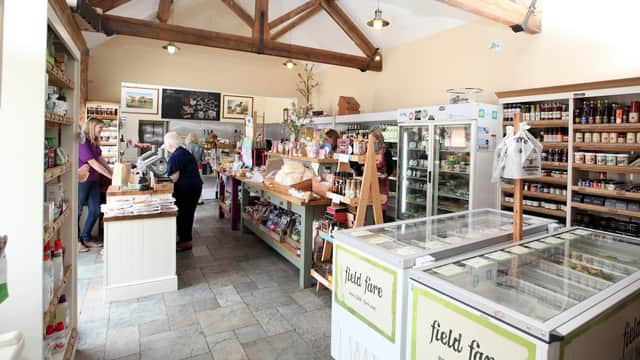 Bright shop interior with wooden beams, shelves filled with local products, and customers at the counter.
