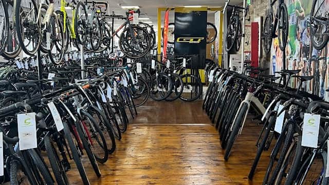 Bikes displayed on racks in a well-lit shop with wooden flooring, showcasing a variety of models and accessories.