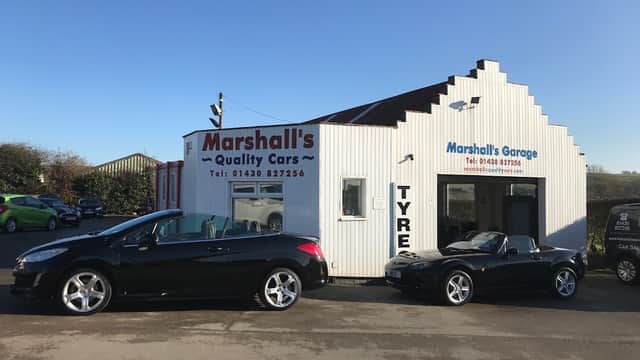 Marshalls Quality Cars dealership with two black cars parked outside and a white building featuring signage and contact info.