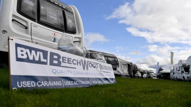 Beechwood Leisure sign in front of a row of caravans and motorhomes on a grassy area under a cloudy sky.