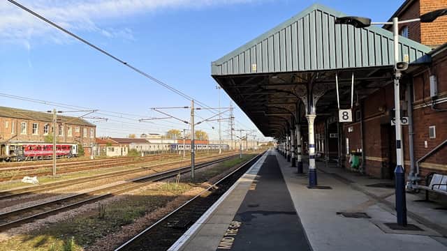 Railway platform at Doncaster station, featuring tracks, trains, and a blue sky with scattered clouds.