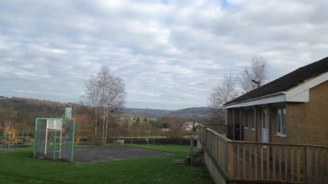View of Darley Playing Fields with a basketball hoop, grassy area, and rolling hills under a cloudy sky.