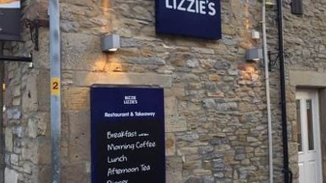 Bizzie Lizzie's restaurant sign on a stone building, featuring menus for breakfast, lunch, and dinner.
