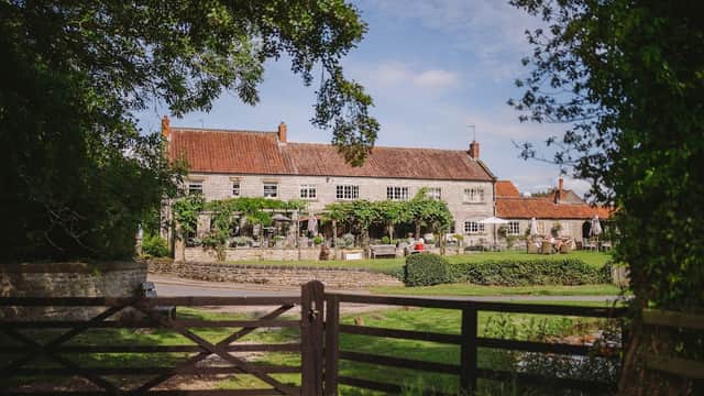 The Pheasant Hotel, a charming stone building with a red-tiled roof, surrounded by greenery and a peaceful landscape.