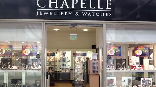 Storefront of Chapelle Jewellery with glass displays showcasing watches and jewelry, featuring sale signs.