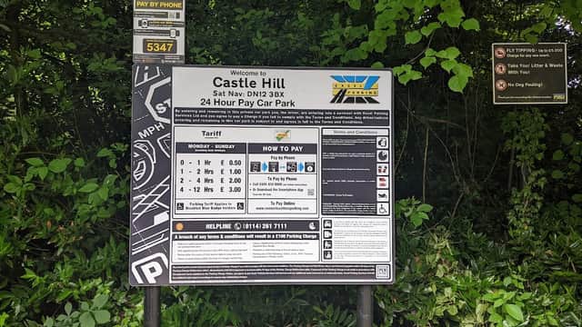 Welcome sign for Castle Hill Car Park with payment instructions, tariffs, and surrounded by greenery.
