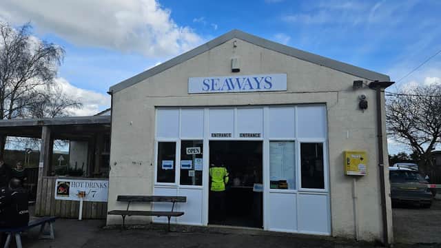 Seaways building with a large sign, open entrance, and outdoor seating area under a cloudy sky.