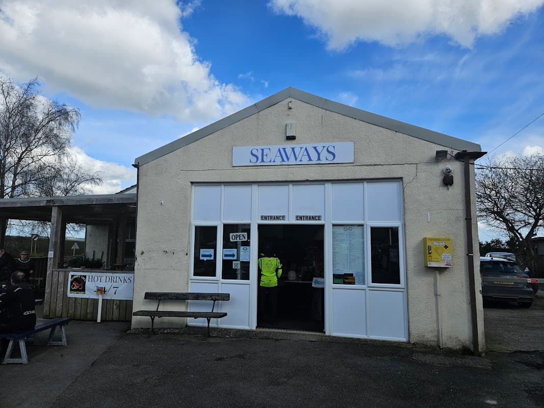 Seaways building with a large sign, open entrance, and outdoor seating area under a cloudy sky.