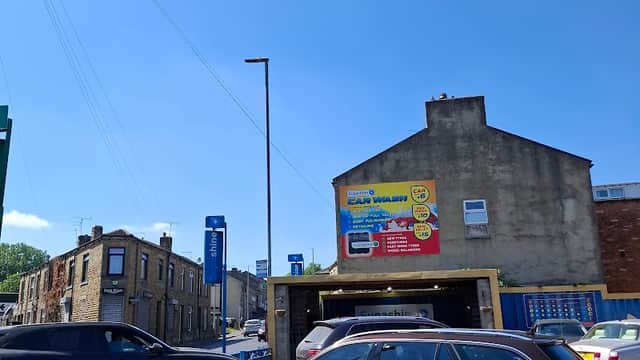 Bright blue sky over SUPA SHINE HAND CAR WASH AND VALETING, with cars parked and a building in Liversedge, Yorkshire.
