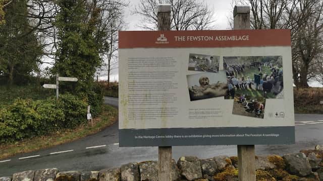 Signpost detailing "The Fewston Assemblage" with countryside backdrop and road intersection in Fewston, Yorkshire.