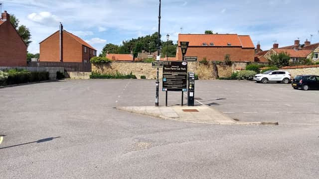 Town Farm Car Park in Kirkbymoorside, featuring a pay station, empty parking spaces, and surrounding residential buildings.
