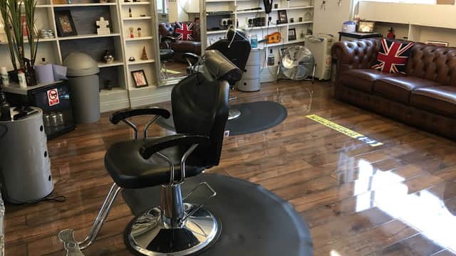 Stylish hair salon interior with a black barber chair, wooden floor, and British flags on display.
