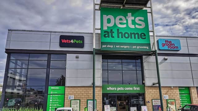 Large pet shop building with green signage, featuring "Pets at Home," "Vets4Pets," and "the groom room." Cars parked outside.