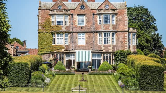 Elegant brick mansion with large windows, surrounded by lush gardens and neatly trimmed hedges in Goldsborough, Yorkshire.