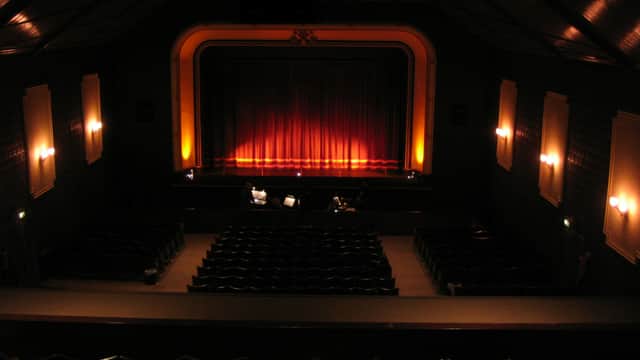 Interior of Pendle Hippodrome Theatre featuring a stage with red curtains and rows of empty seats.