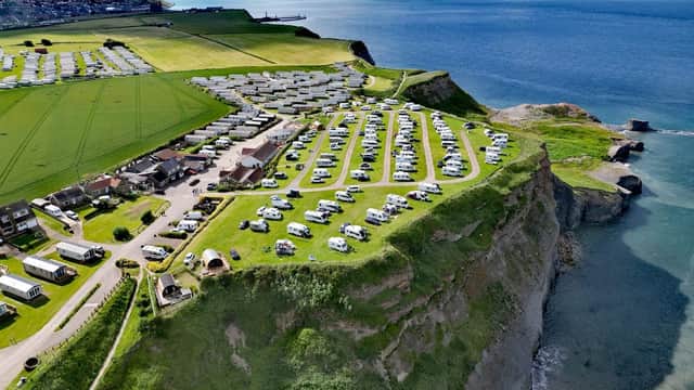 Aerial view of Whitby Holiday Park featuring caravans, green fields, and cliffs overlooking the sea.