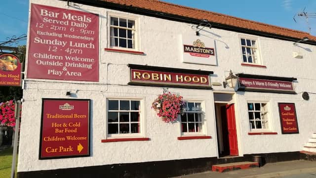 The Robin Hood Inn, a white building with red accents, featuring signs for bar meals, children's welcome, and a car park.