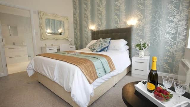 Cozy bedroom with a double bed, light blue floral wallpaper, champagne, strawberries, and elegant decor.