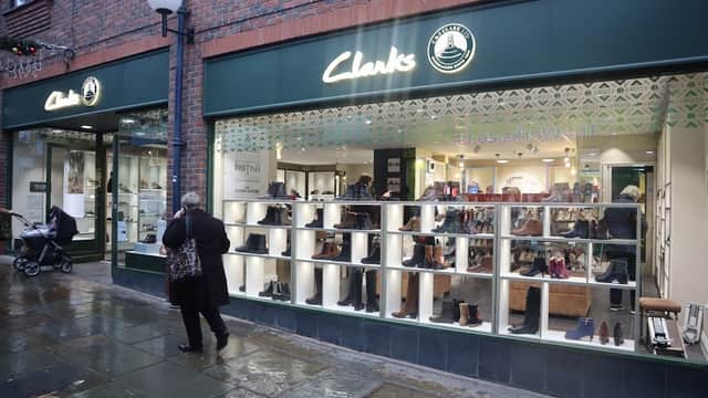 Clarks shoe shop exterior in Harrogate, showcasing a variety of shoes in display windows; rainy pavement visible.