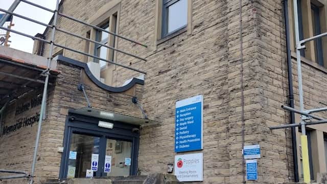 Stone building with scaffolding, entrance steps, and signage for Holme Valley Memorial Hospital in Yorkshire.