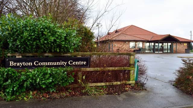 Brayton Community Centre sign with greenery and brick building in the background, cloudy sky above.